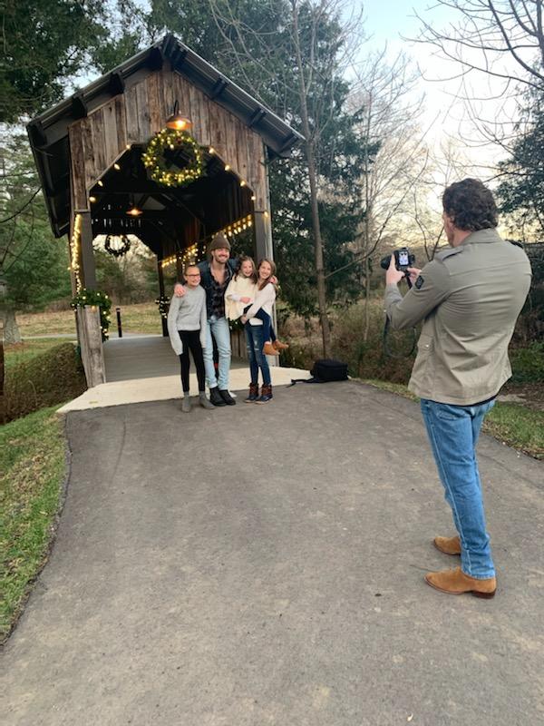 A family posing for a photo by a bridge