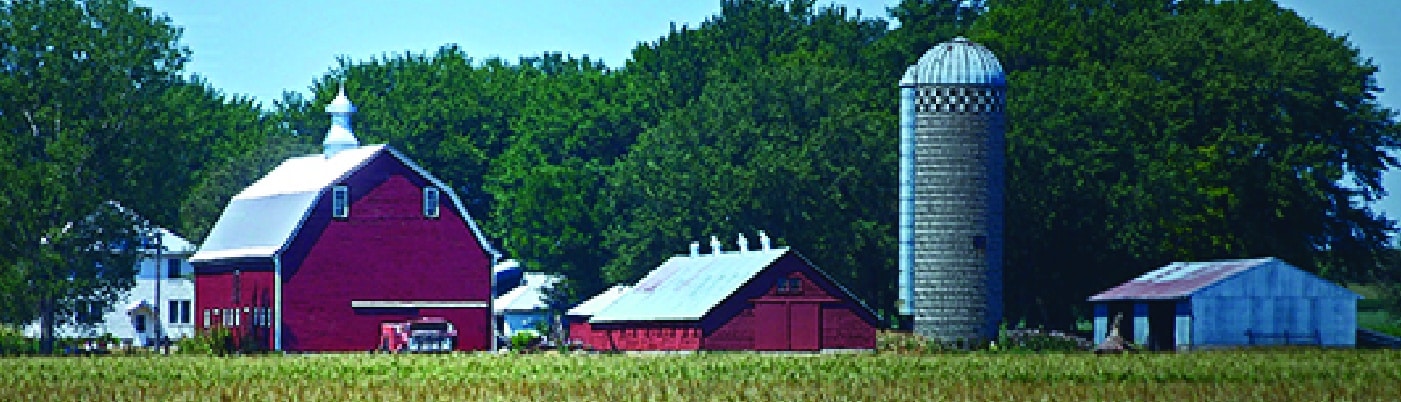 A red barn in a field with trees in the background