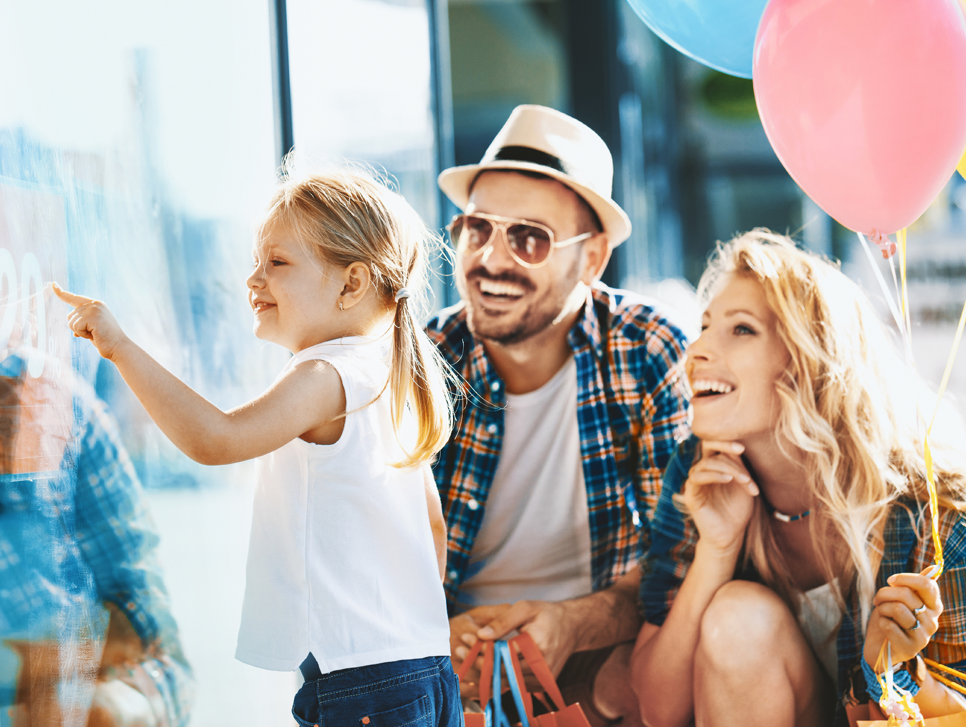 A family of three looking at a sign, and the mom is holding balloons